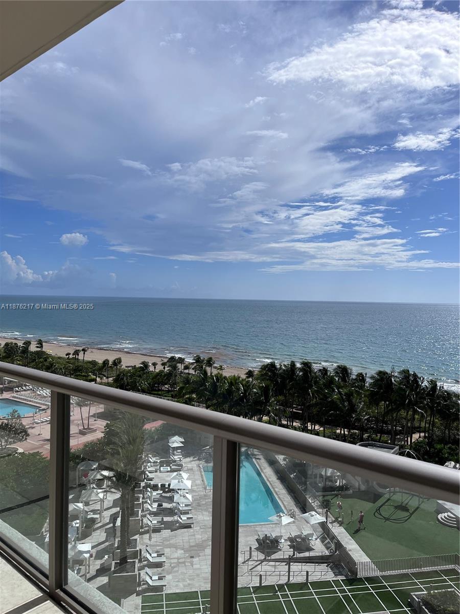 A balcony view overlooks a swimming pool, palm trees, a sandy beach, and the ocean — 9705 Collins Ave # 903N, Bal Harbour FL 33154, BAL HARBOUR, FL