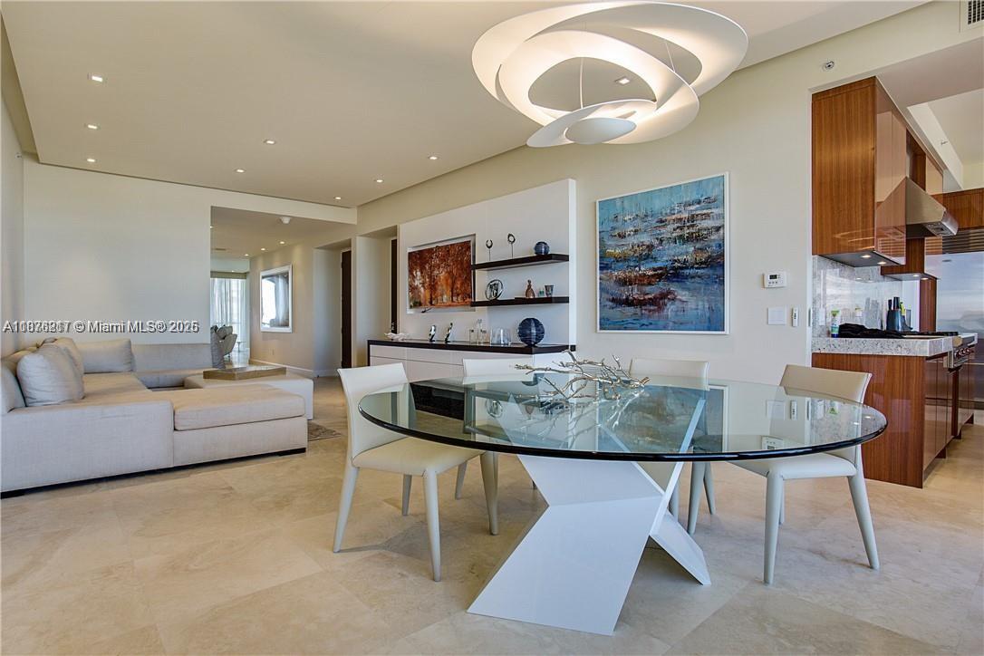 A modern dining area features a glass-topped table, white chairs, and a sculptural light fixture — 9705 Collins Ave # 903N, Bal Harbour FL 33154, BAL HARBOUR, FL