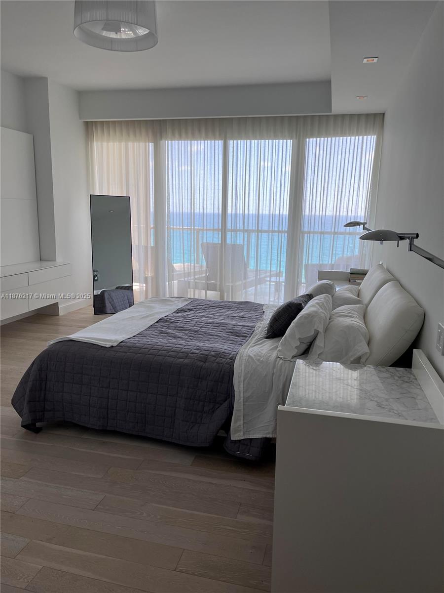 A modern bedroom features a bed, marble-topped furniture, and floor-to-ceiling windows overlooking the ocean — 9705 Collins Ave # 903N, Bal Harbour FL 33154, BAL HARBOUR, FL