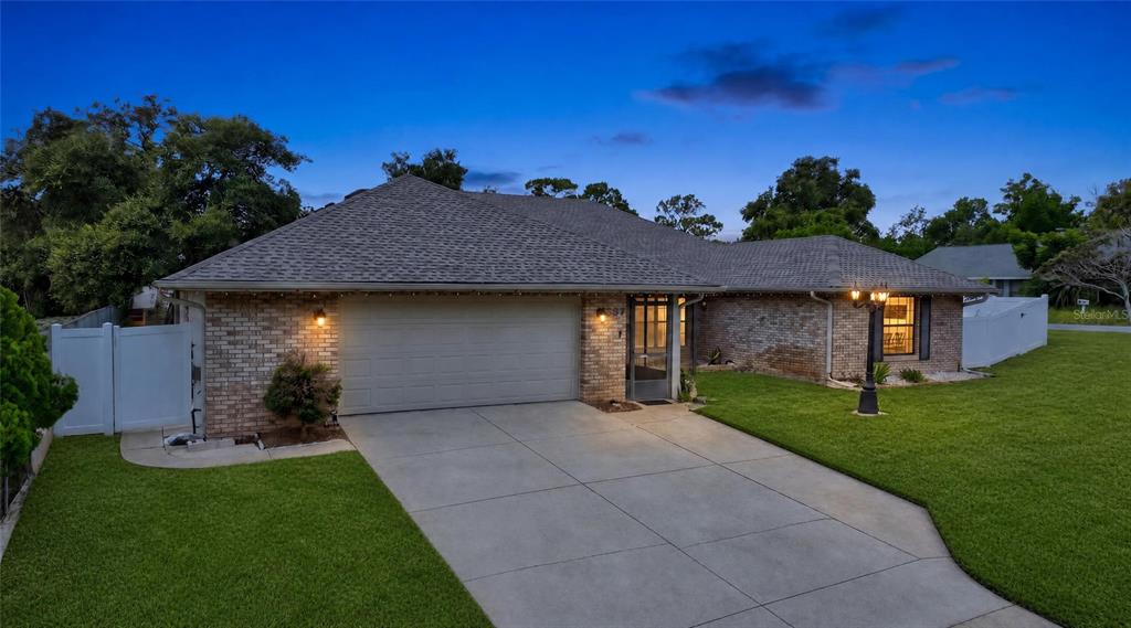 A single-story brick house with a two-car garage and a concrete driveway at twilight — 937 UTICA STREET, DELTONA, FL
