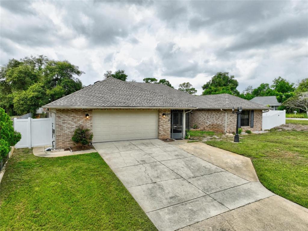 A single-story brick house with a two-car garage and a concrete driveway — 937 UTICA STREET, DELTONA, FL