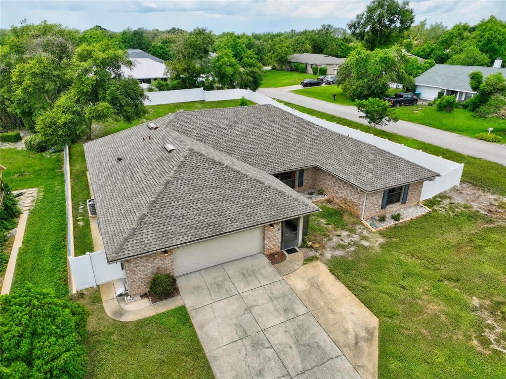 An aerial view of a single-story brick house with a gray shingled roof and driveway — 937 UTICA STREET, DELTONA, FL