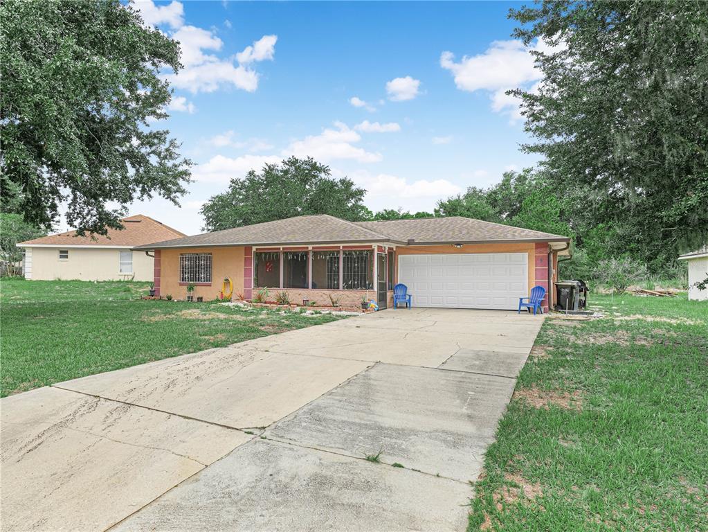 A single-story house with a concrete driveway, a two-car garage, and a screened-in front porch — 5 TUNA LANE, POINCIANA, FL