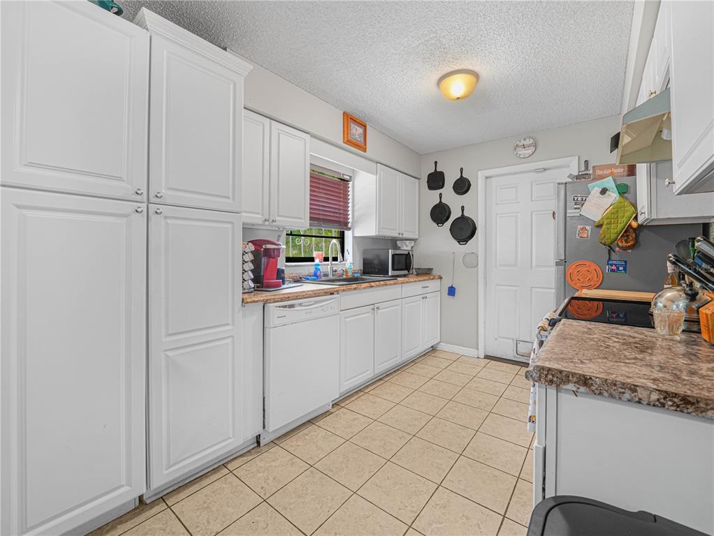 A kitchen with white cabinets, a dishwasher, a sink, and a tiled floor — 5 TUNA LANE, POINCIANA, FL