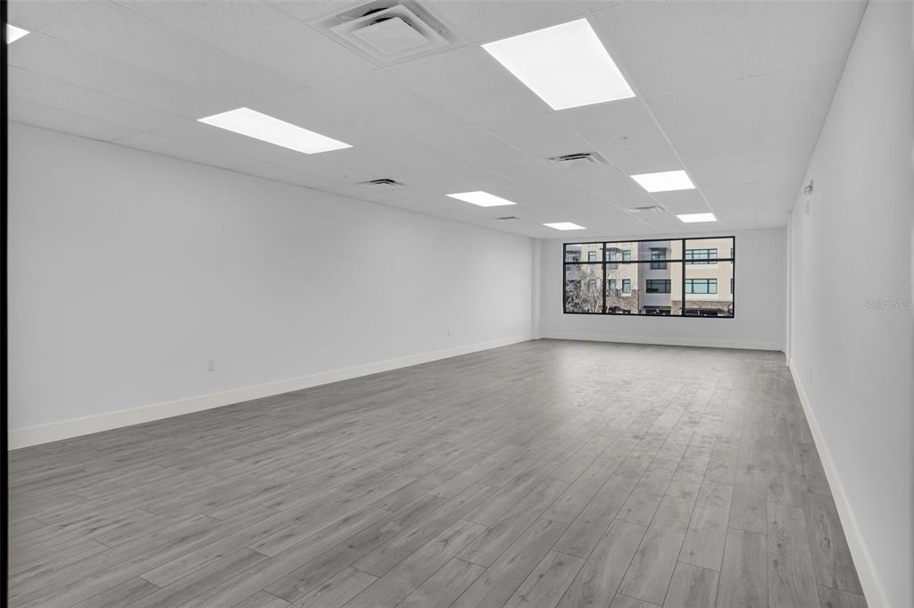 An empty office space with white walls, gray wood-look flooring, and recessed ceiling lights — 13564 VILLAGE PARK DRIVE UNIT 215, ORLANDO, FL