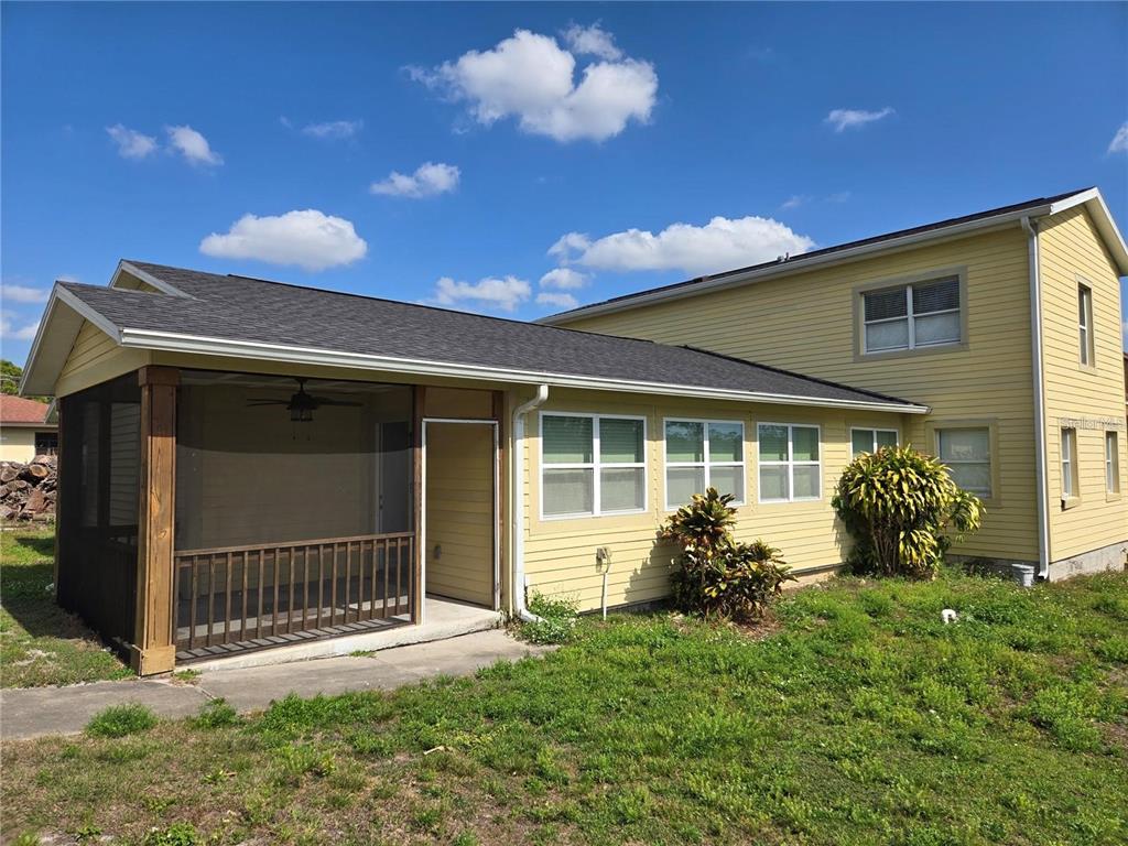 A yellow two-story house features a screened-in porch and a grassy yard under a blue sky — 8725 TWIN LAKES BOULEVARD, TAMPA, FL
