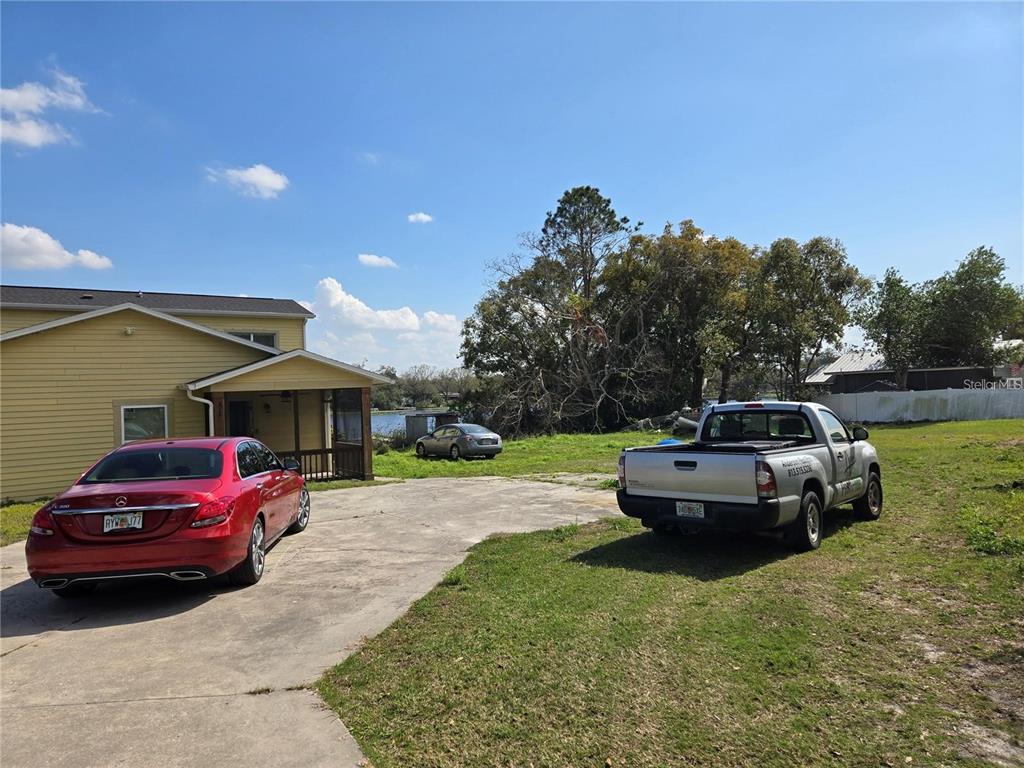 A yellow house with a concrete driveway, two parked vehicles, and a view of water — 8725 TWIN LAKES BOULEVARD, TAMPA, FL
