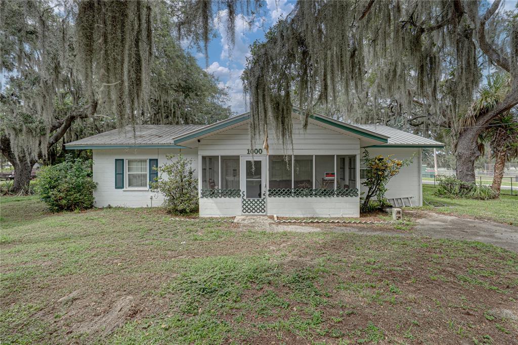 A single-story white house with a metal roof and a screened-in front porch — 1000 ALTON STREET, AVON PARK, FL