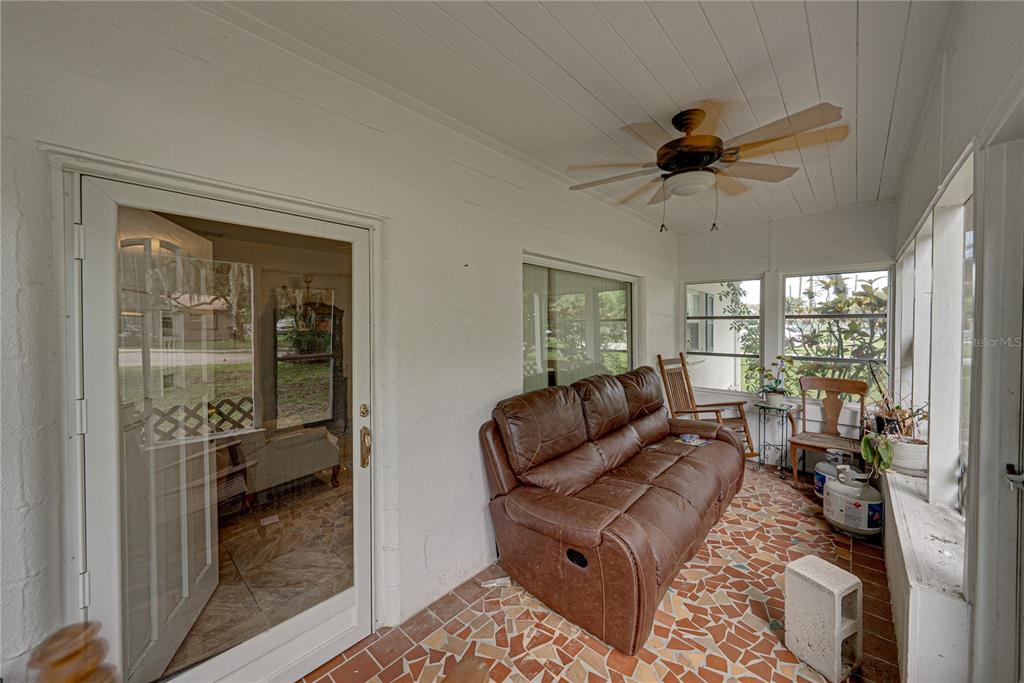A sunroom features a brown leather sofa, a ceiling fan, and a mosaic tile floor — 1000 ALTON STREET, AVON PARK, FL