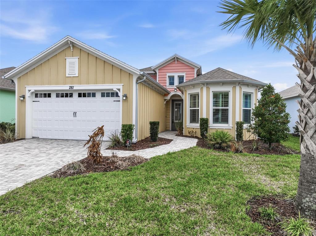 A yellow house with a white garage door, pink gable, and a paved walkway — 281 MARGARITAVILLE AVENUE, DAYTONA BEACH, FL