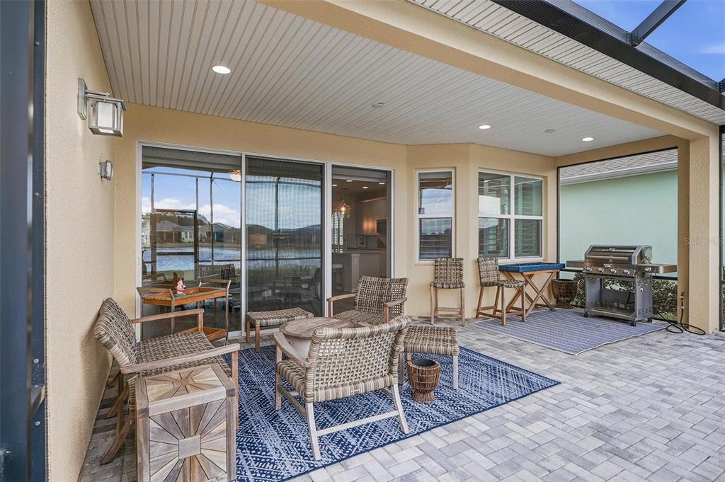 A covered patio features wicker furniture, a blue patterned rug, and a stainless steel grill — 281 MARGARITAVILLE AVENUE, DAYTONA BEACH, FL