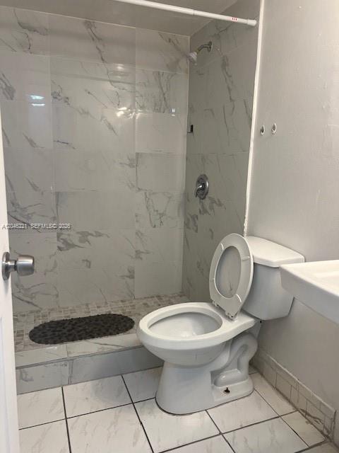 A bathroom features a white toilet and a walk-in shower with marble-patterned tile walls — 5775 W 20th Ave # 310, Hialeah FL 33012, HIALEAH, FL