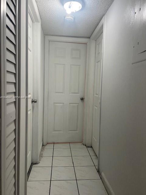 A narrow hallway with white walls, tiled flooring, and three closed doors — 5775 W 20th Ave # 310, Hialeah FL 33012, HIALEAH, FL