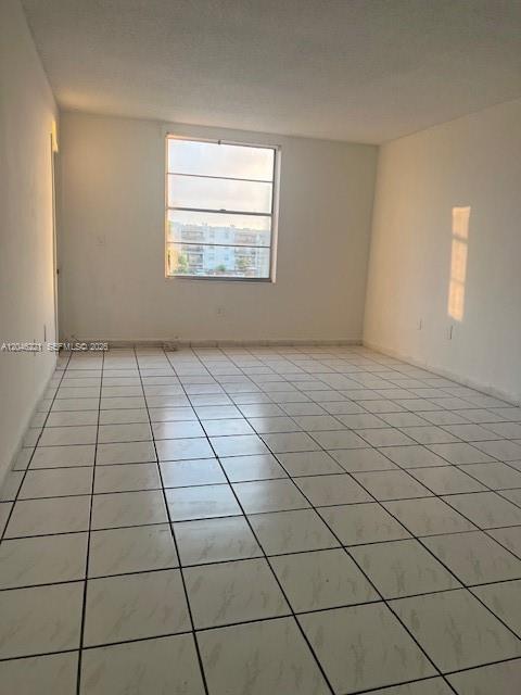 An empty room with white tile flooring and a large window overlooking a building — 5775 W 20th Ave # 310, Hialeah FL 33012, HIALEAH, FL