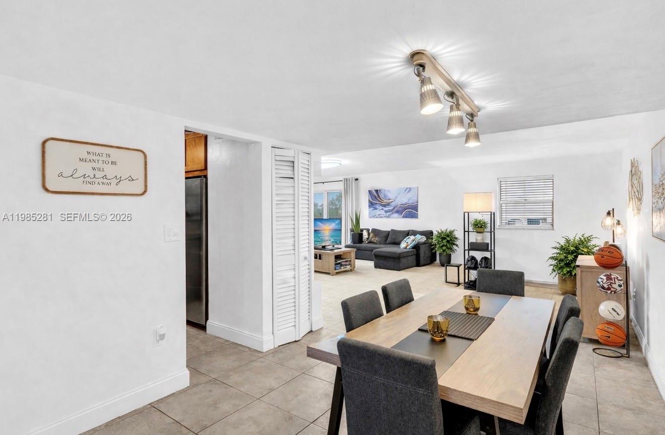 A dining area with a wooden table and grey chairs opens into a living room — 1236 Alton Rd # 304, Miami Beach FL 33139, MIAMI BEACH, FL
