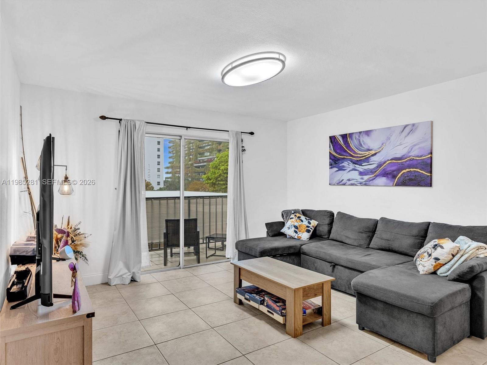 A living room features a gray sectional sofa, a coffee table, and a sliding glass door — 1236 Alton Rd # 304, Miami Beach FL 33139, MIAMI BEACH, FL