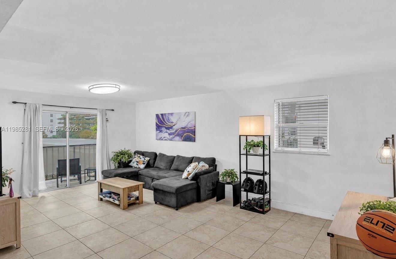 A living room features tile flooring, a gray sectional sofa, and a sliding glass door — 1236 Alton Rd # 304, Miami Beach FL 33139, MIAMI BEACH, FL