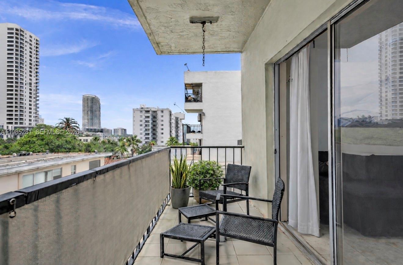 A balcony with outdoor furniture overlooks a city skyline with several high-rise buildings — 1236 Alton Rd # 304, Miami Beach FL 33139, MIAMI BEACH, FL