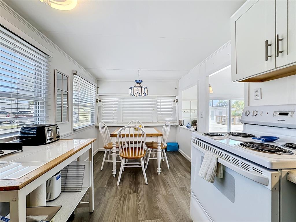 A kitchen and dining area with white cabinets, a white stove, and wood-look flooring — 10315 CORTEZ ROAD W UNIT 58-3, BRADENTON, FL