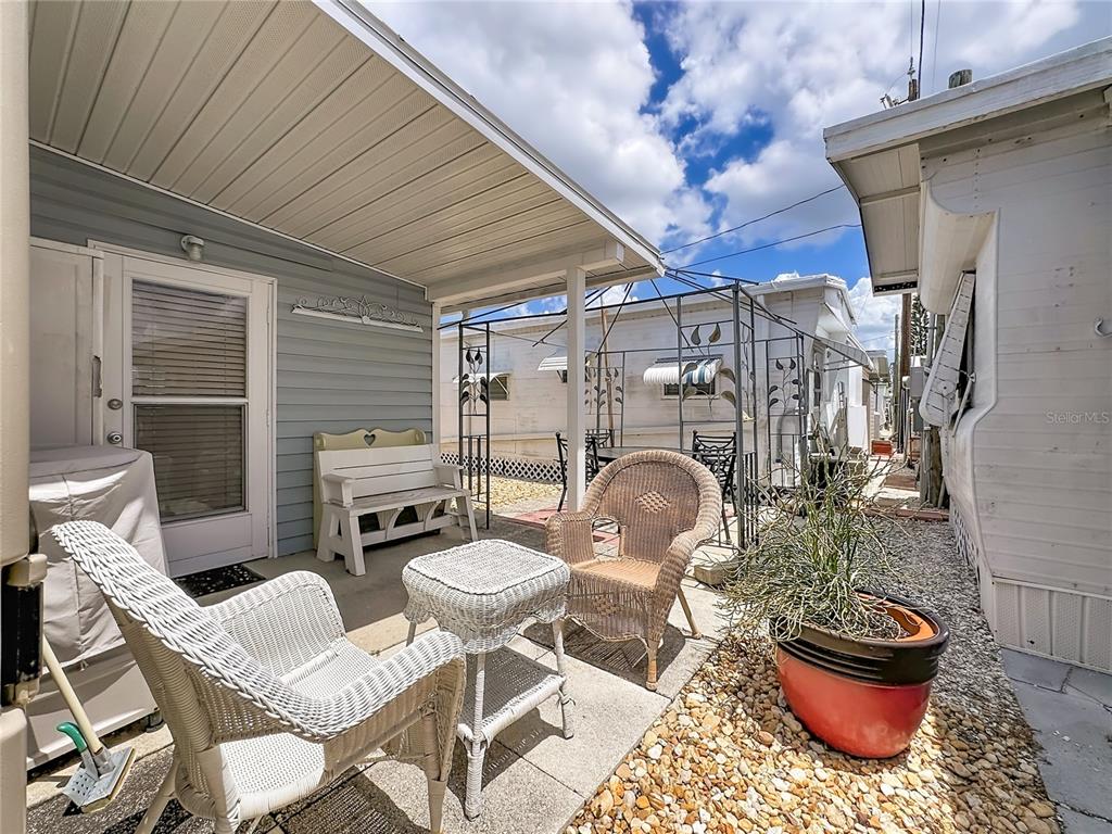 A patio area features wicker furniture, a white bench, and a potted plant outdoors — 10315 CORTEZ ROAD W UNIT 58-3, BRADENTON, FL