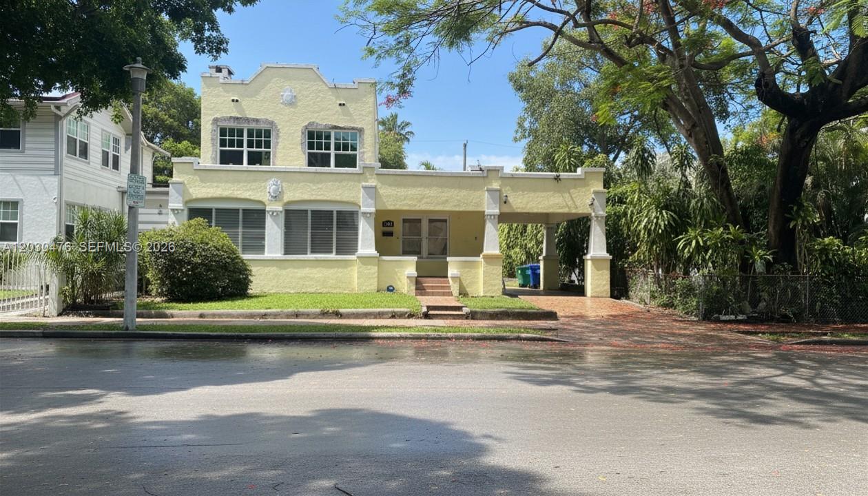 A two-story yellow stucco house features a flat roof, a carport, and a front lawn — MIAMI, FL