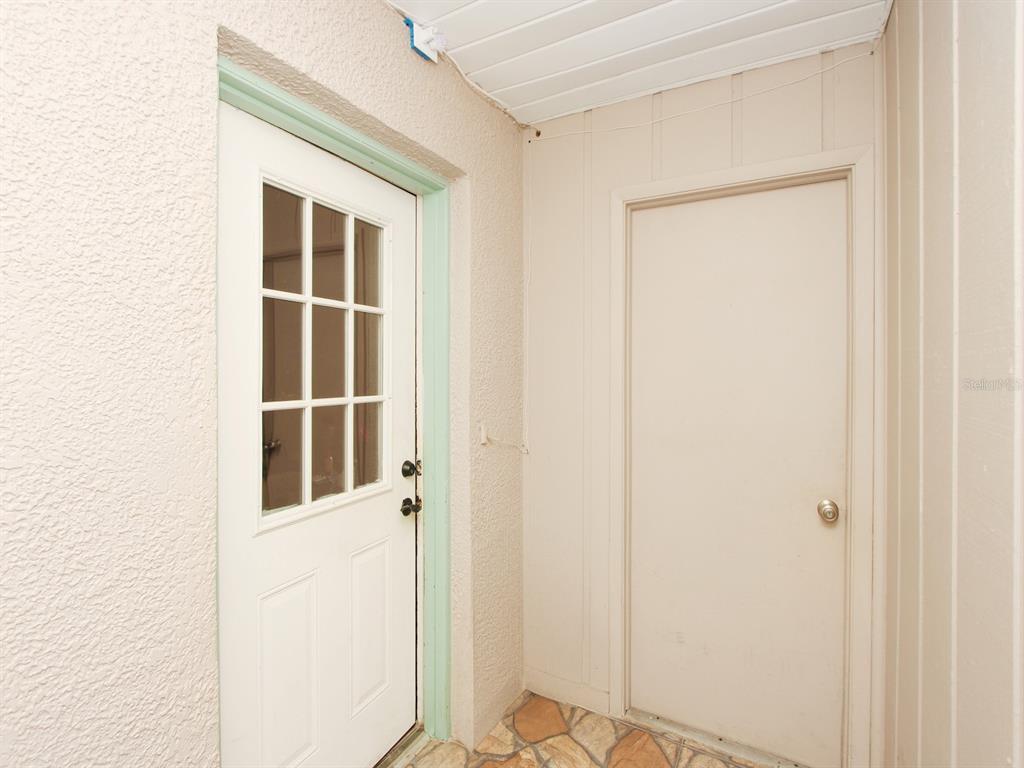 A white door with glass panes sits next to a solid door on a patio — 4173 SIGNAL HILL ROAD, ORLANDO, FL
