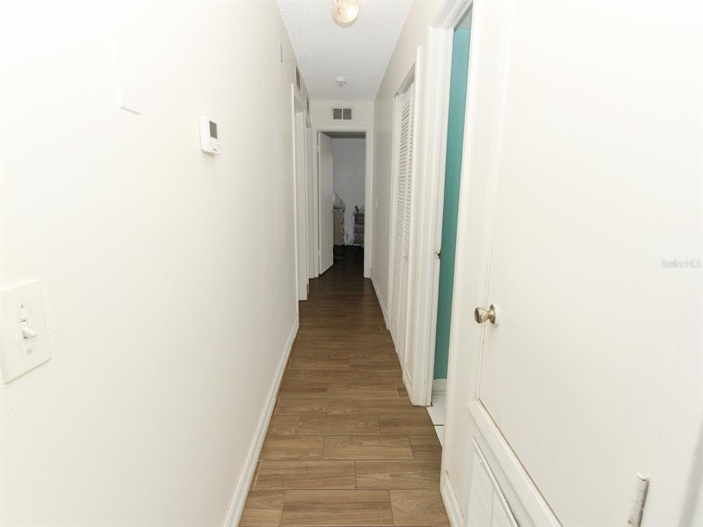 A narrow hallway features wood-look tile flooring, white walls, and several closed interior doors — 4173 SIGNAL HILL ROAD, ORLANDO, FL