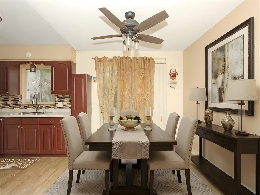 A dining area with a dark wood table, upholstered chairs, and an adjacent kitchen — 4173 SIGNAL HILL ROAD, ORLANDO, FL