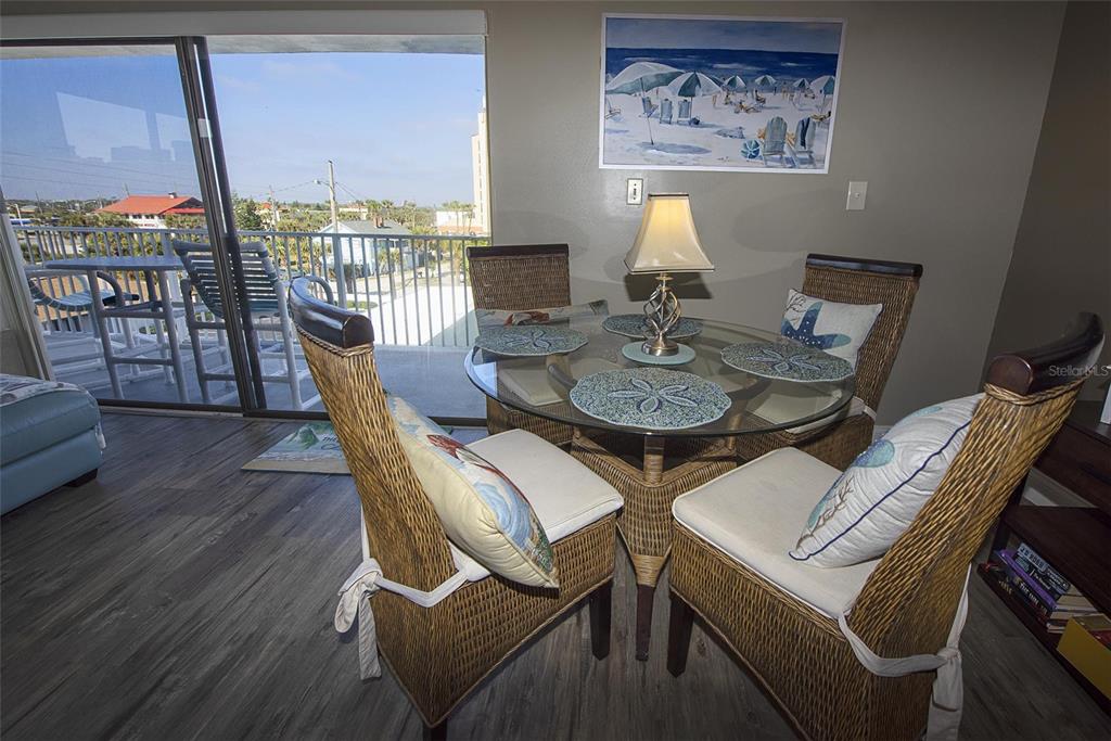 A dining area features a glass-topped wicker table with four chairs and a balcony view — 1571 S ATLANTIC AVENUE UNIT 412, NEW SMYRNA BEACH, FL