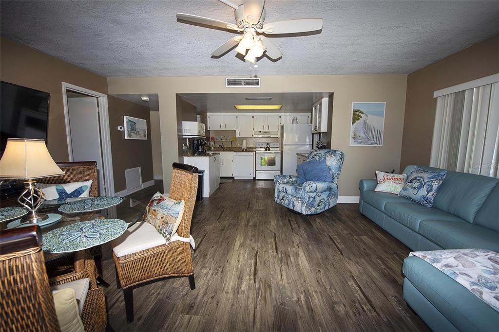 An open-concept living and dining area features wood-look flooring, a ceiling fan, and a kitchen — 1571 S ATLANTIC AVENUE UNIT 412, NEW SMYRNA BEACH, FL