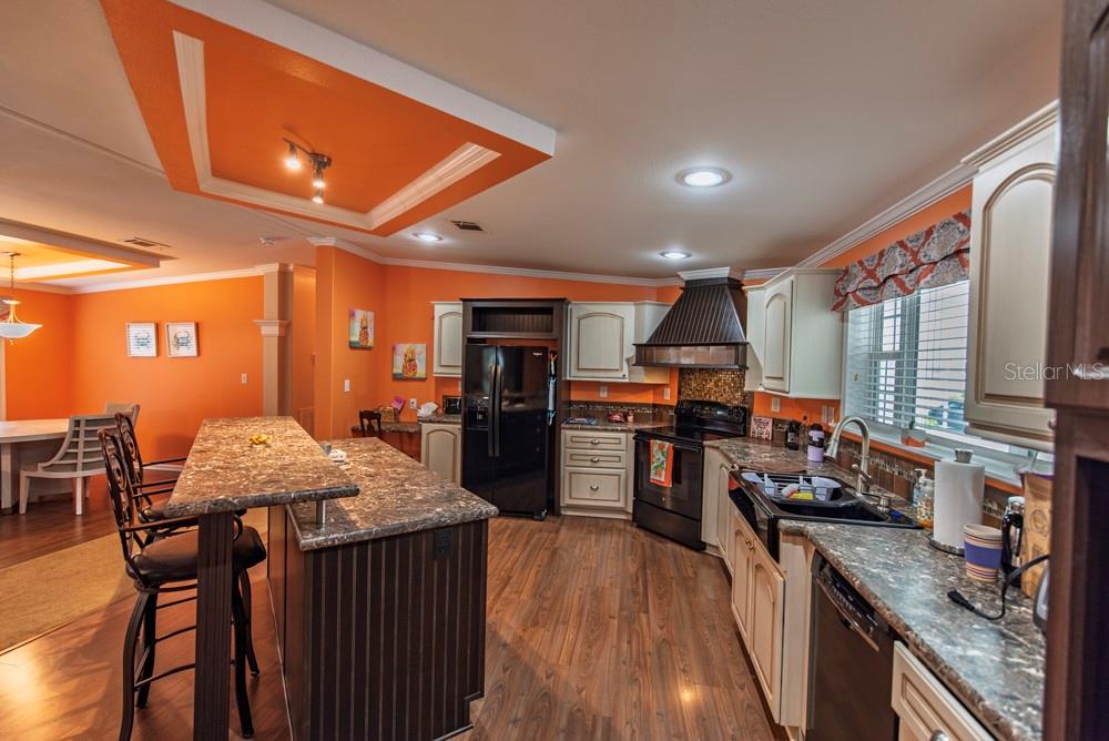 A kitchen with orange walls, a large granite island, and dark wood-style flooring — 11 BRINK AVENUE, PUNTA GORDA, FL