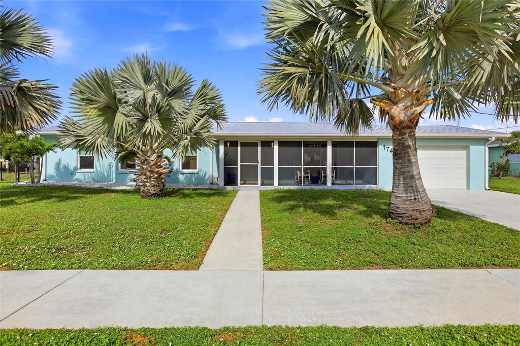 A light blue single-story house features a screened front porch, a garage, and palm trees — 174 SEVERIN ROAD SE, PORT CHARLOTTE, FL