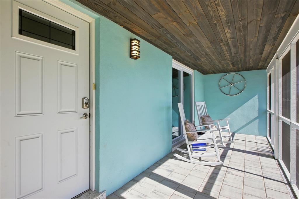 A covered porch with light blue walls, a wood-plank ceiling, and two white rocking chairs — 174 SEVERIN ROAD SE, PORT CHARLOTTE, FL