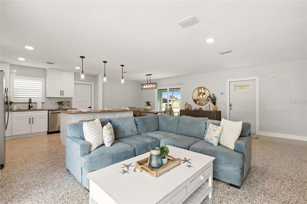 An open-concept living room features a blue sectional sofa, a white coffee table, and kitchen — 174 SEVERIN ROAD SE, PORT CHARLOTTE, FL