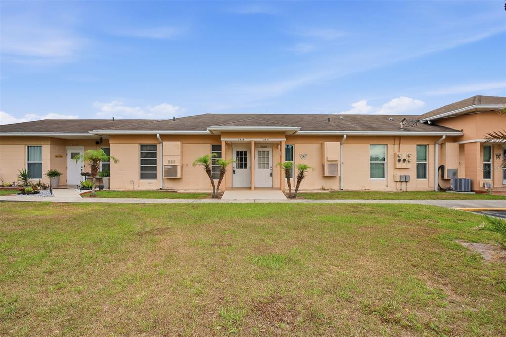 A single-story, peach-colored apartment building with multiple entry doors and a grassy front lawn — 2629 CLUB CIRCLE UNIT 2629, LAKE WALES, FL