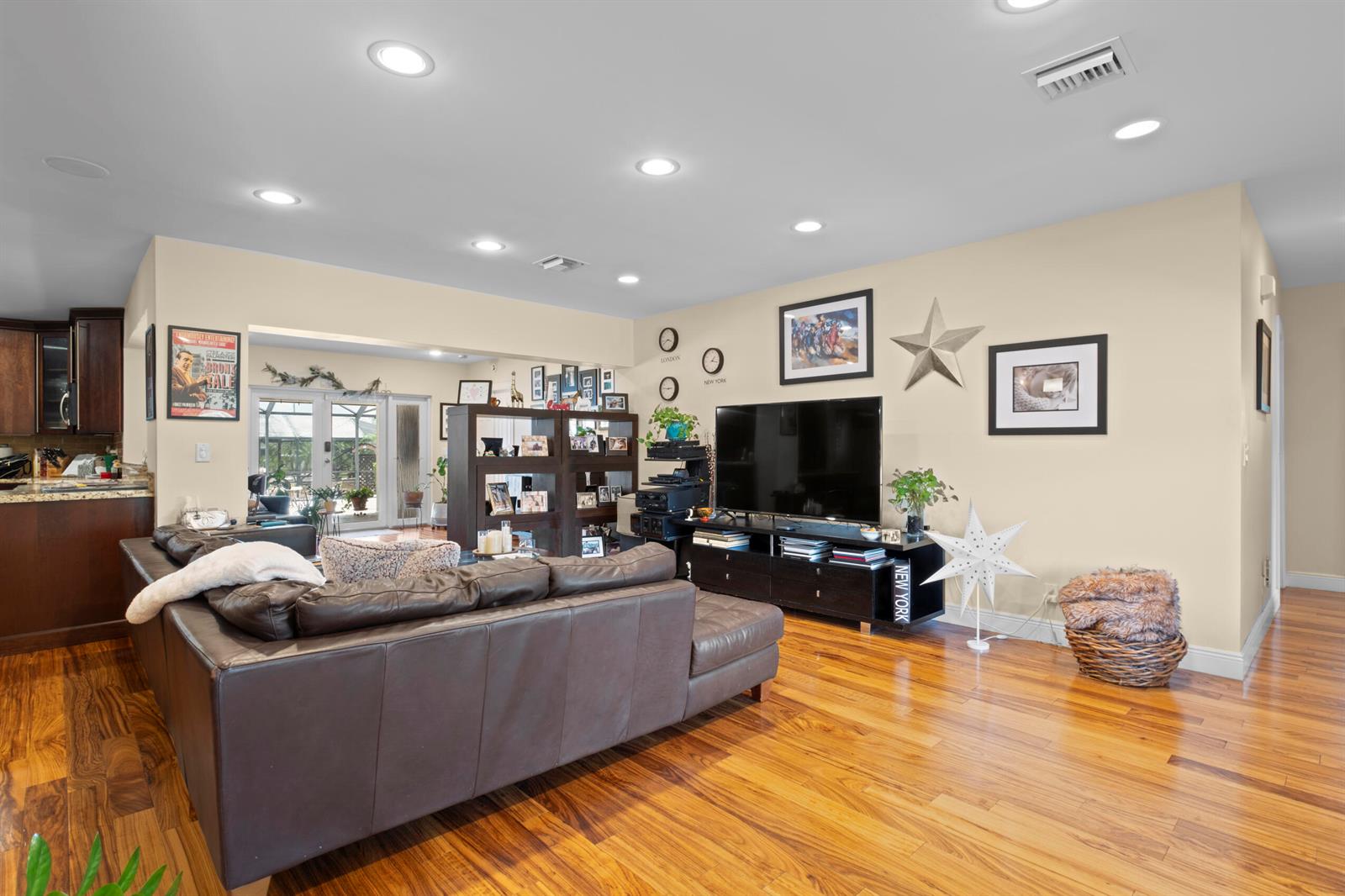 A living room with a brown leather sectional, hardwood floors, and a television on a stand — 2700 NE 4th Way, Boca Raton FL 33431, BOCA RATON, FL