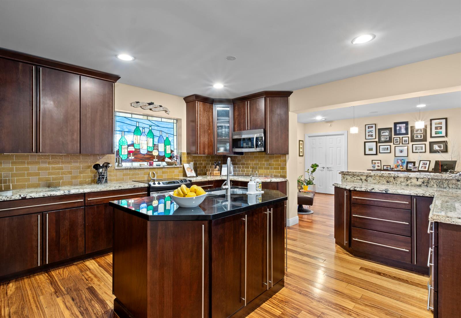 A kitchen features dark wood cabinets, granite countertops, a central island, and a stained-glass window — 2700 NE 4th Way, Boca Raton FL 33431, BOCA RATON, FL