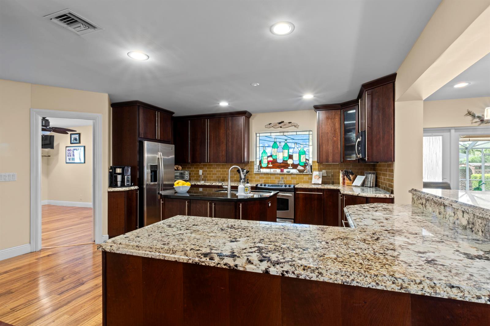 A kitchen features dark wood cabinets, granite countertops, a stained glass window, and stainless appliances — 2700 NE 4th Way, Boca Raton FL 33431, BOCA RATON, FL