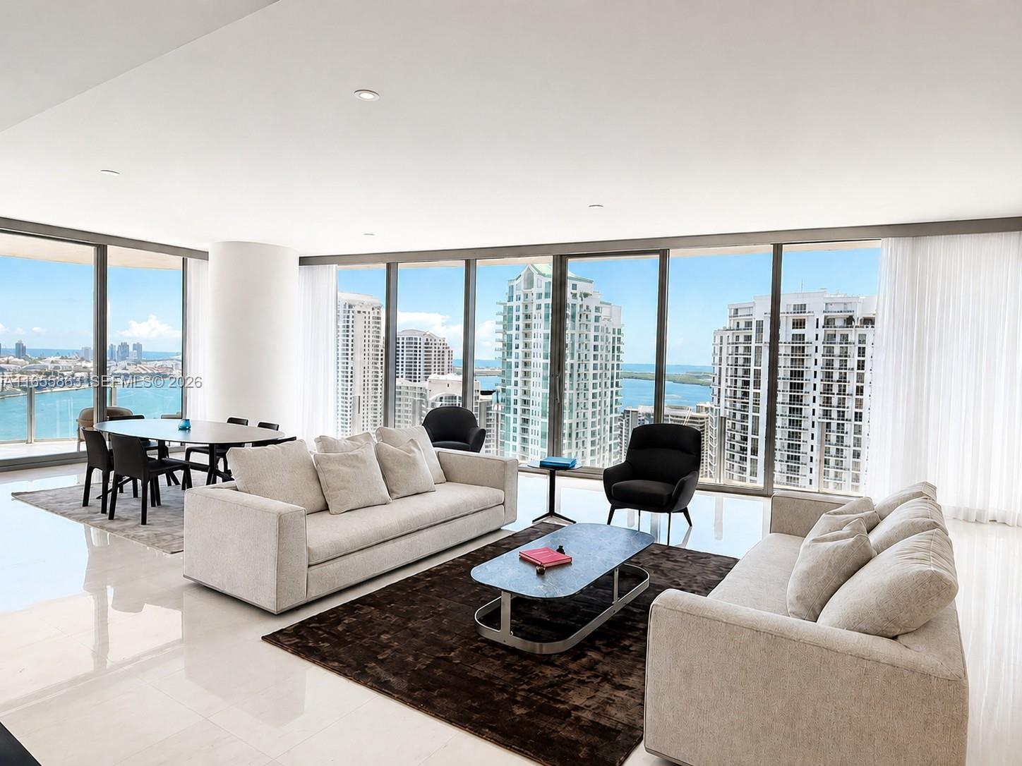 A modern living and dining area features floor-to-ceiling windows with expansive city and water views — 300 Biscayne Blvd Way # 3201, Miami FL 33131, MIAMI, FL