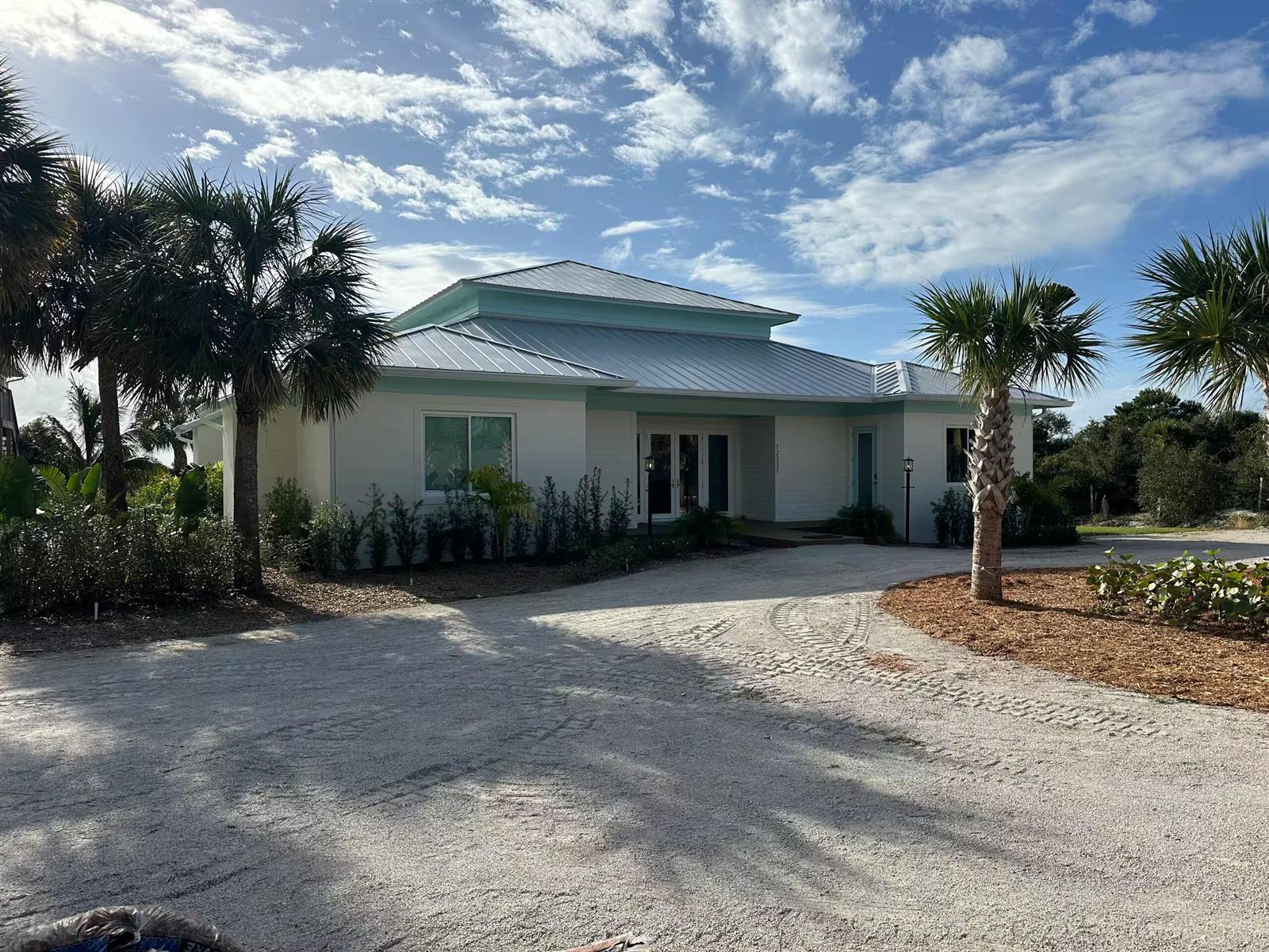 A single-story house with a metal roof and light-colored siding sits behind a gravel driveway — 12331 S Indian River Drive, Jensen Beach FL 34957, JENSEN BEACH, FL