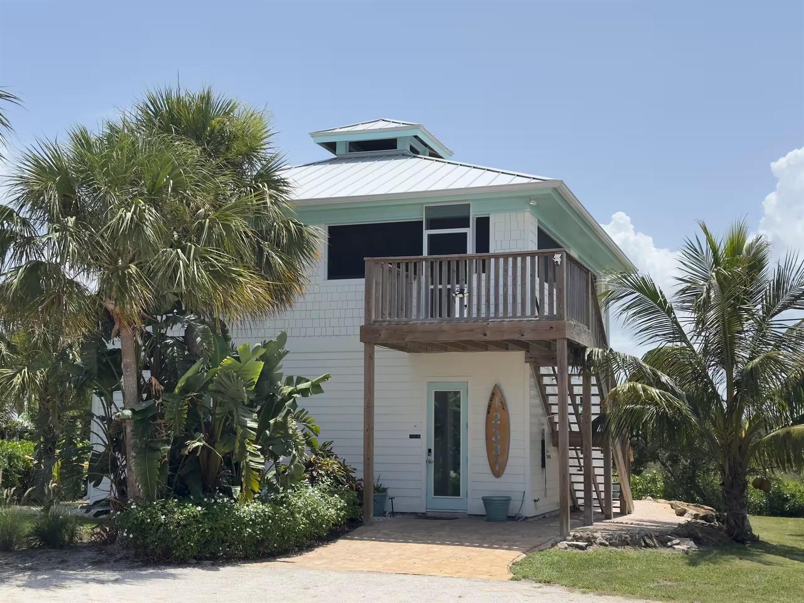 A two-story white house with a metal roof, wooden balcony, and palm trees in front — 12331 S Indian River Drive, Jensen Beach FL 34957, JENSEN BEACH, FL