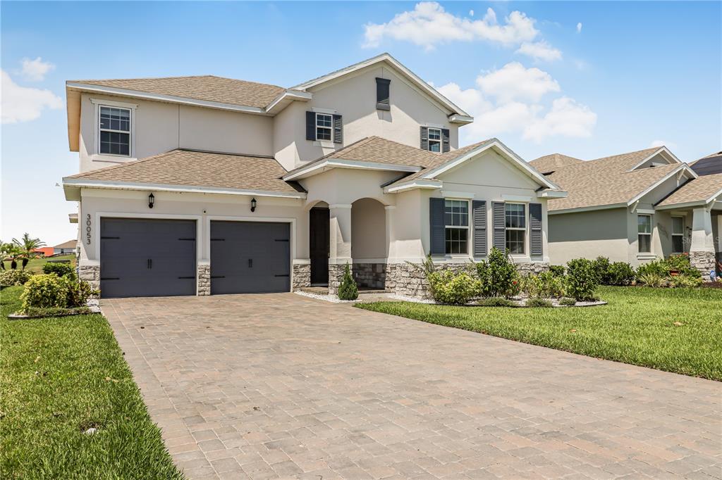 A two-story house with a two-car garage, stone accents, and a paved driveway — 30053 ISLAND CLUB DRIVE, DEER ISLAND, FL