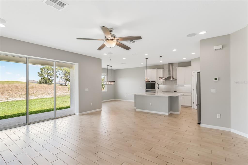 An open-concept kitchen and living area features light wood-look tile floors and sliding glass doors — 30053 ISLAND CLUB DRIVE, DEER ISLAND, FL