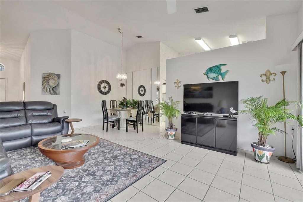 A living room features a black leather sofa, a dining area, and a television console — 6447 PINE WALK DRIVE, NEW PORT RICHEY, FL