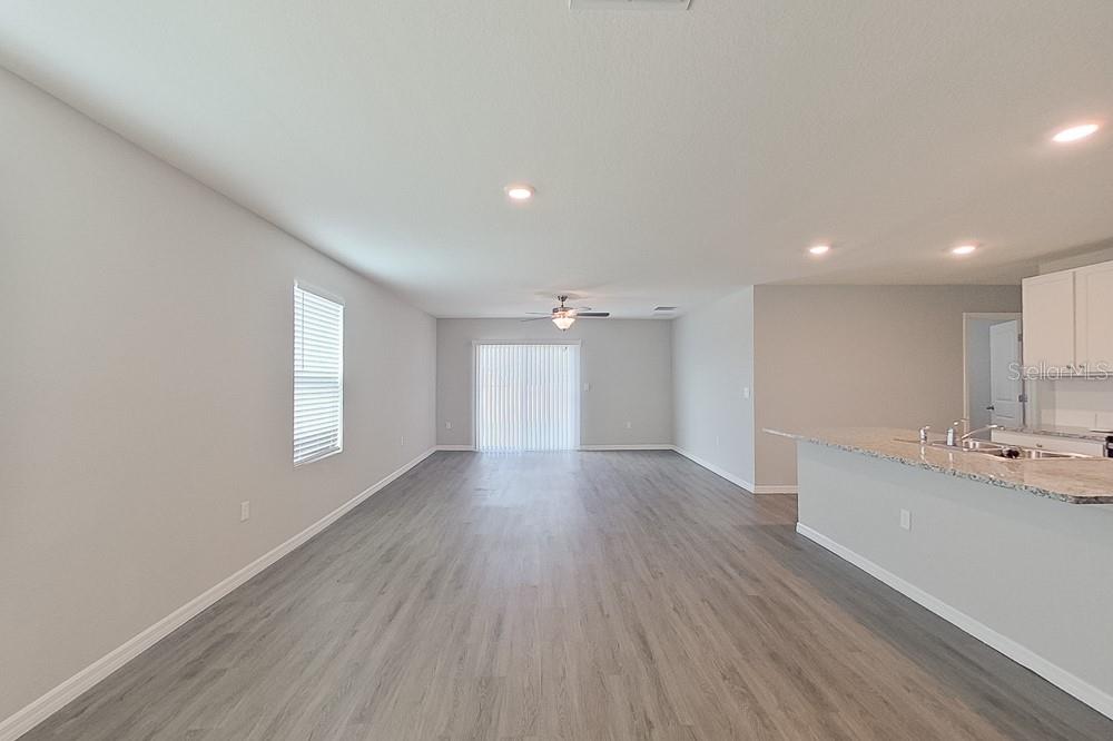 An open-concept living area features light gray walls, wood-look flooring, and a kitchen island — 8740 SW 43RD TERRACE, OCALA, FL