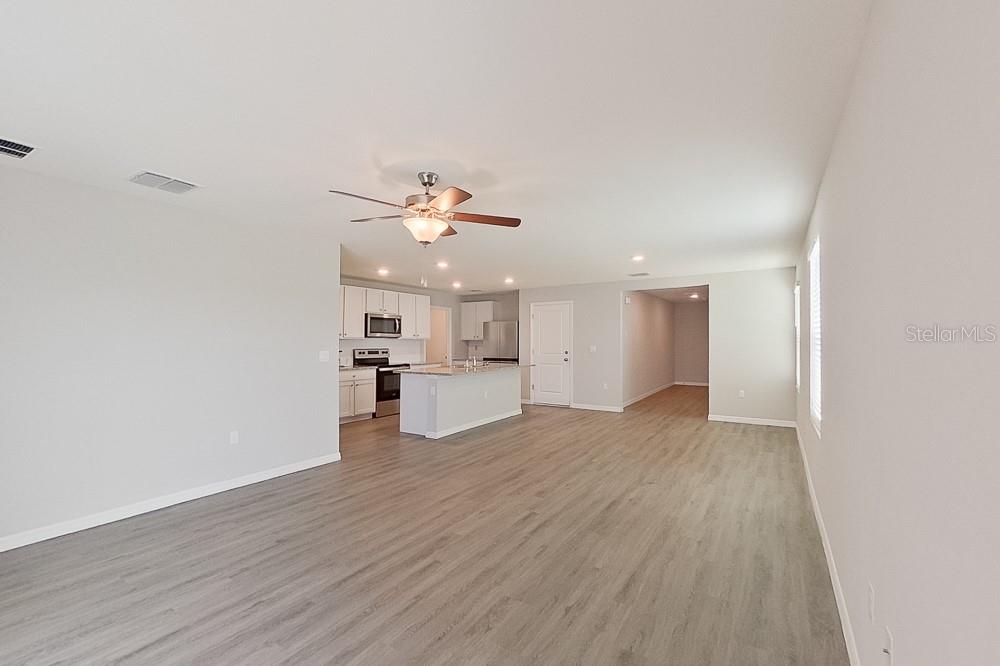 An open-concept living area features light wood-look flooring, a kitchen island, and a ceiling fan — 8740 SW 43RD TERRACE, OCALA, FL