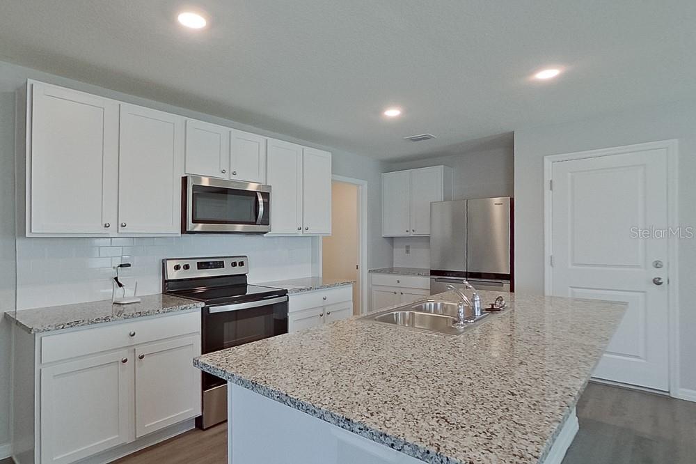 A kitchen features white cabinets, granite countertops, stainless steel appliances, and a central island — 8740 SW 43RD TERRACE, OCALA, FL