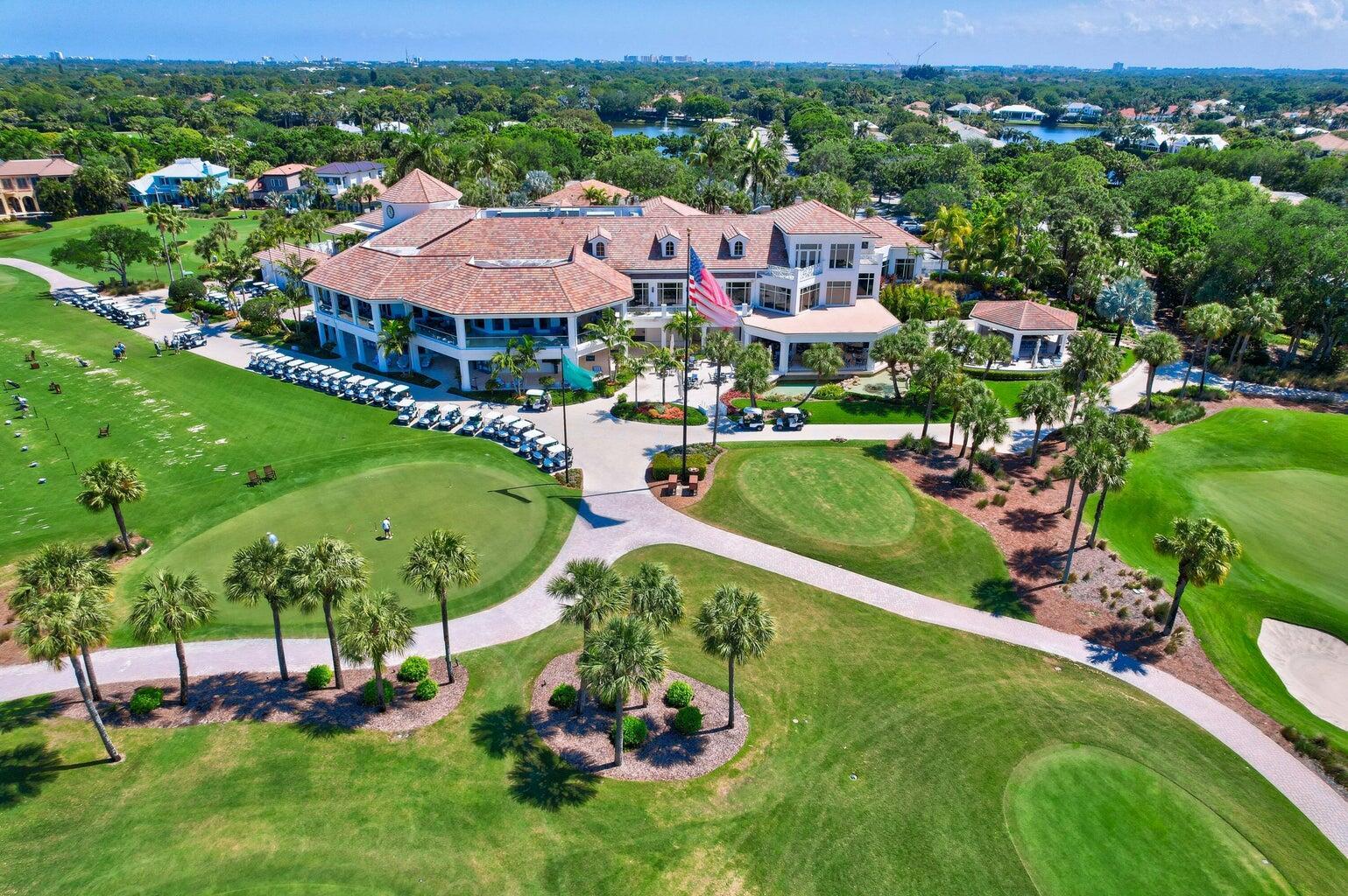 An aerial view of a large clubhouse with a tiled roof surrounded by golf course greens — 187 Birkdale Lane, Jupiter FL 33458, JUPITER, FL