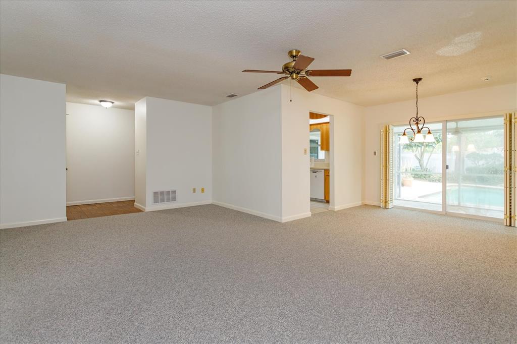 A spacious living room with gray carpet, a ceiling fan, and sliding doors to a pool — 1192 LADY SUSAN DRIVE, CASSELBERRY, FL