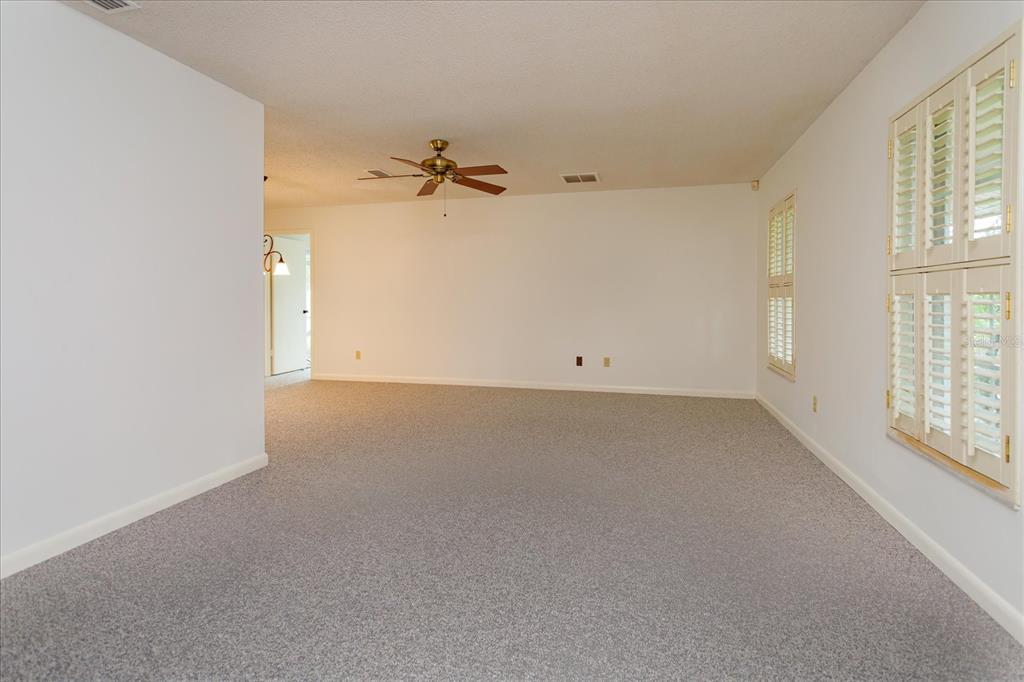 A carpeted living room features a ceiling fan, white walls, and plantation shutters on windows — 1192 LADY SUSAN DRIVE, CASSELBERRY, FL